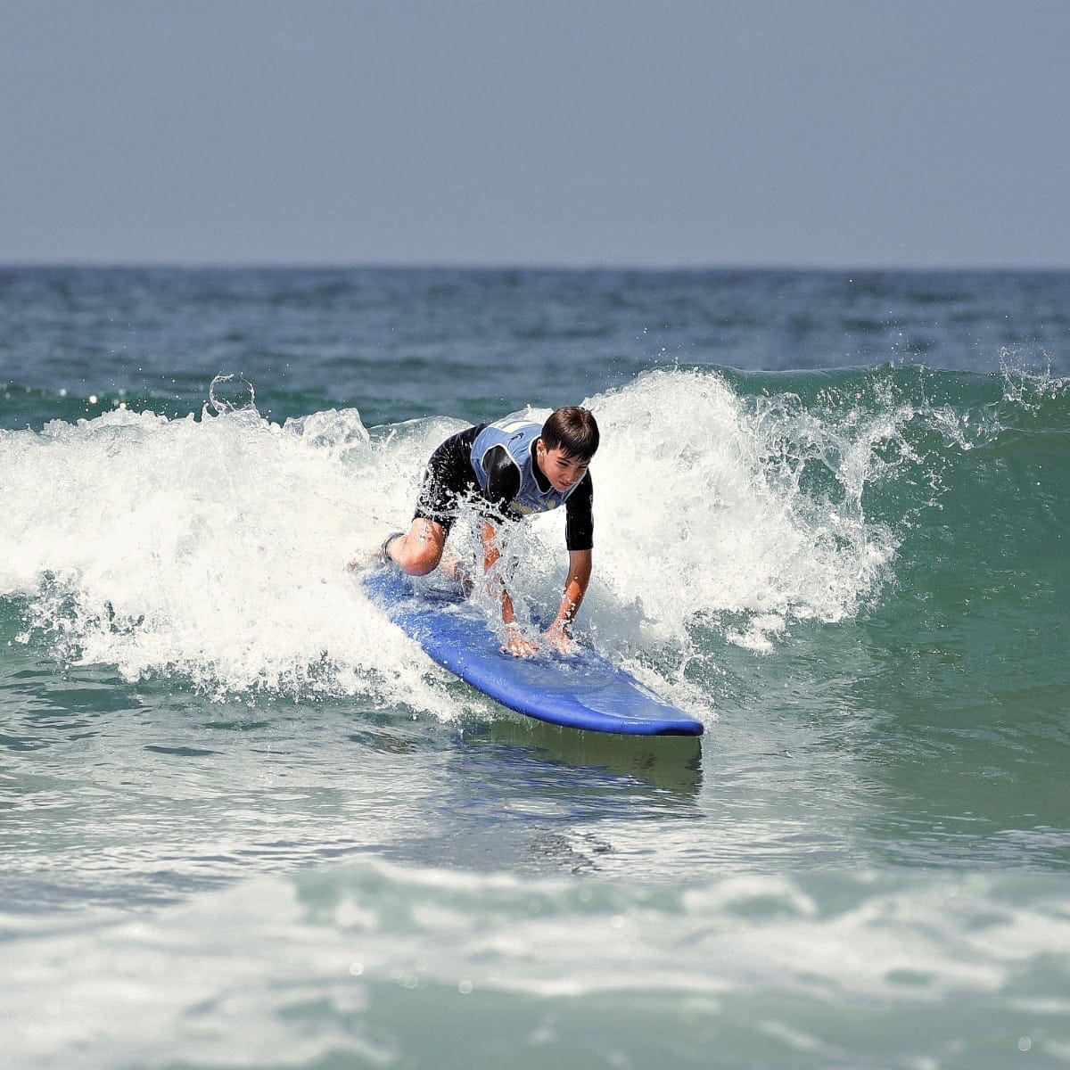 Un adolescent se lève sur sa planche de surf.